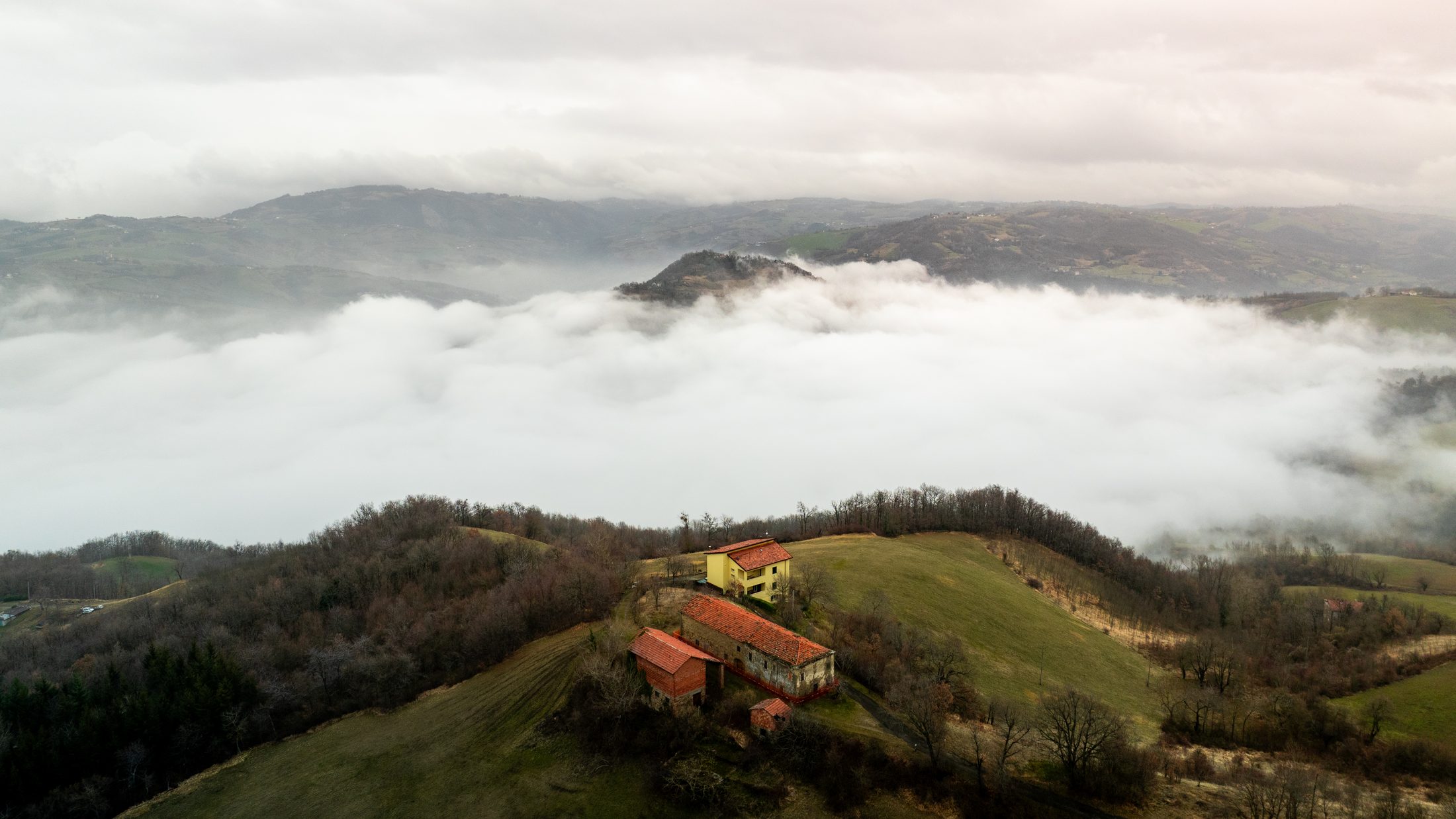 Casa Lunga Nuova rising above the cloud sea — aerial view