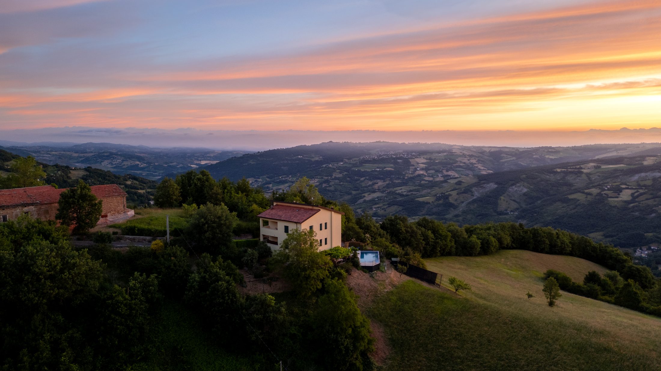 Casa Lunga Nuova at sunset, seen from above with the valley beyond
