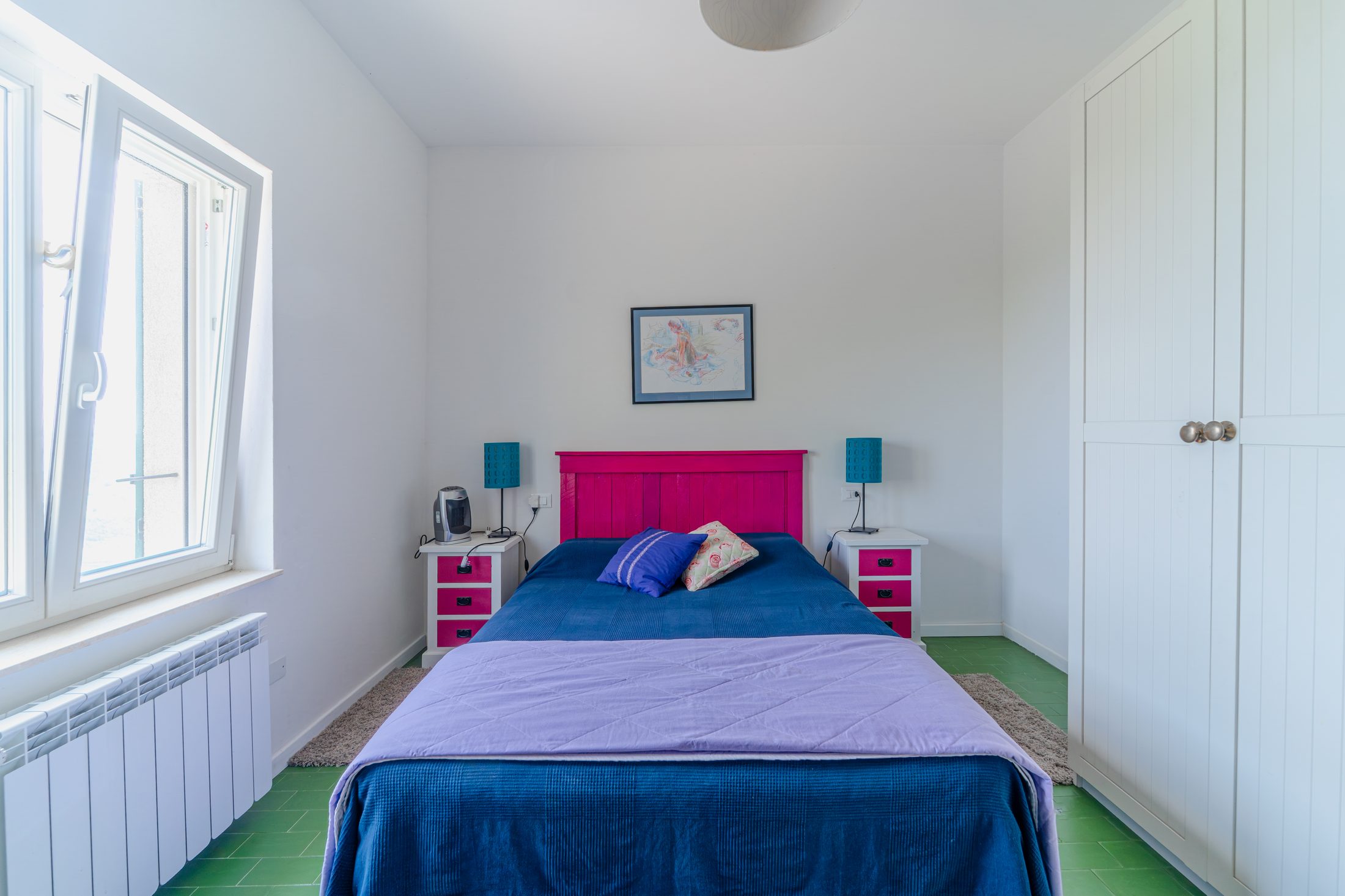 Colourful bedroom with pink headboard and green floor tiles