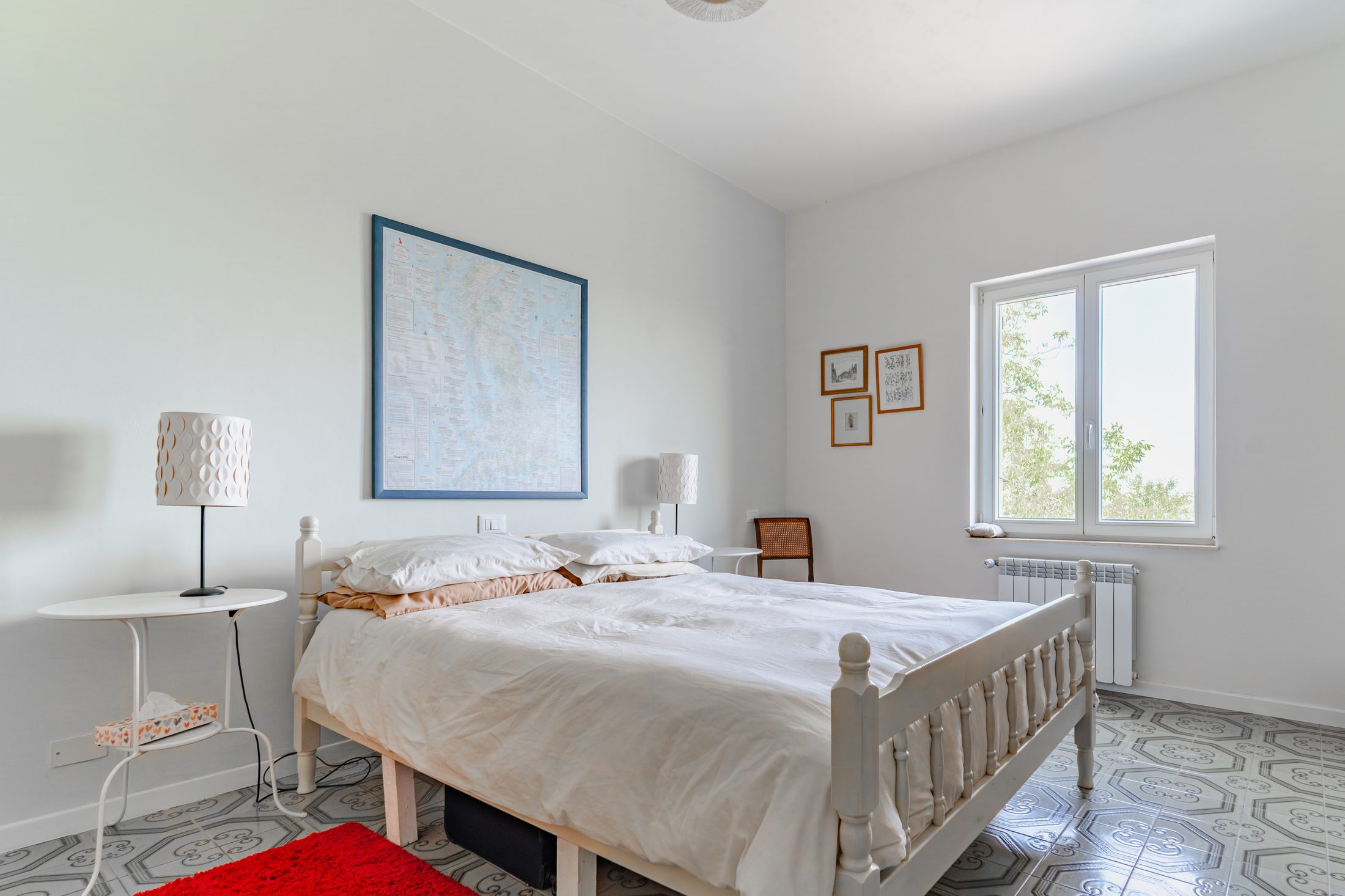 Same bedroom with cane chair and window view