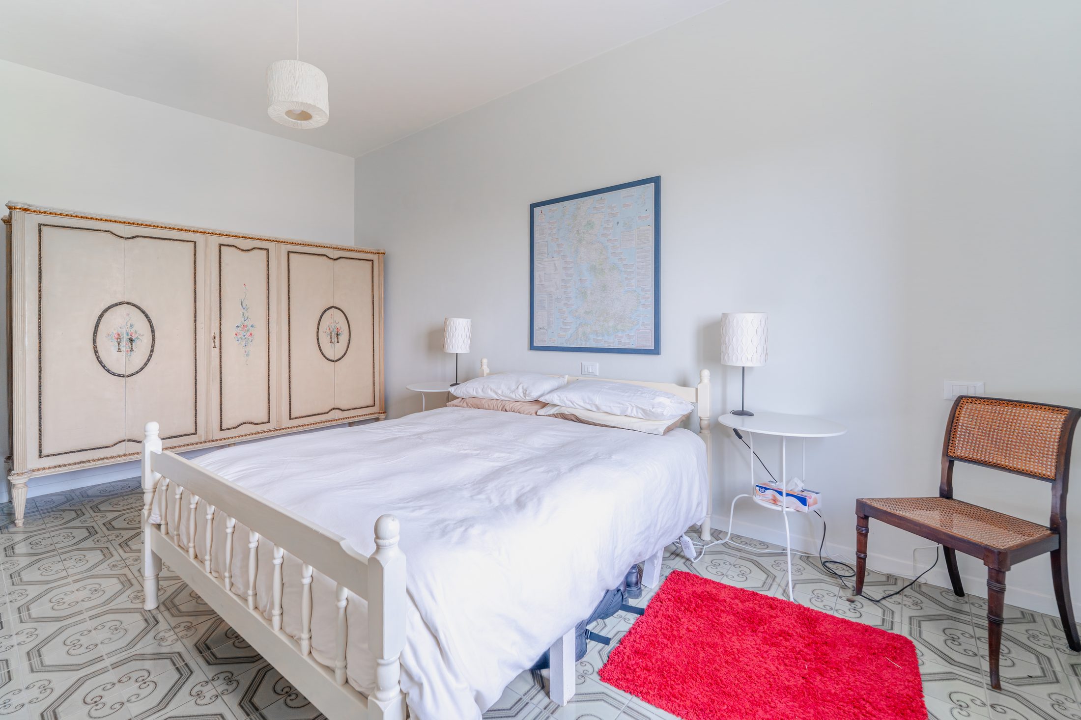 Bedroom with antique painted wardrobe and map on the wall