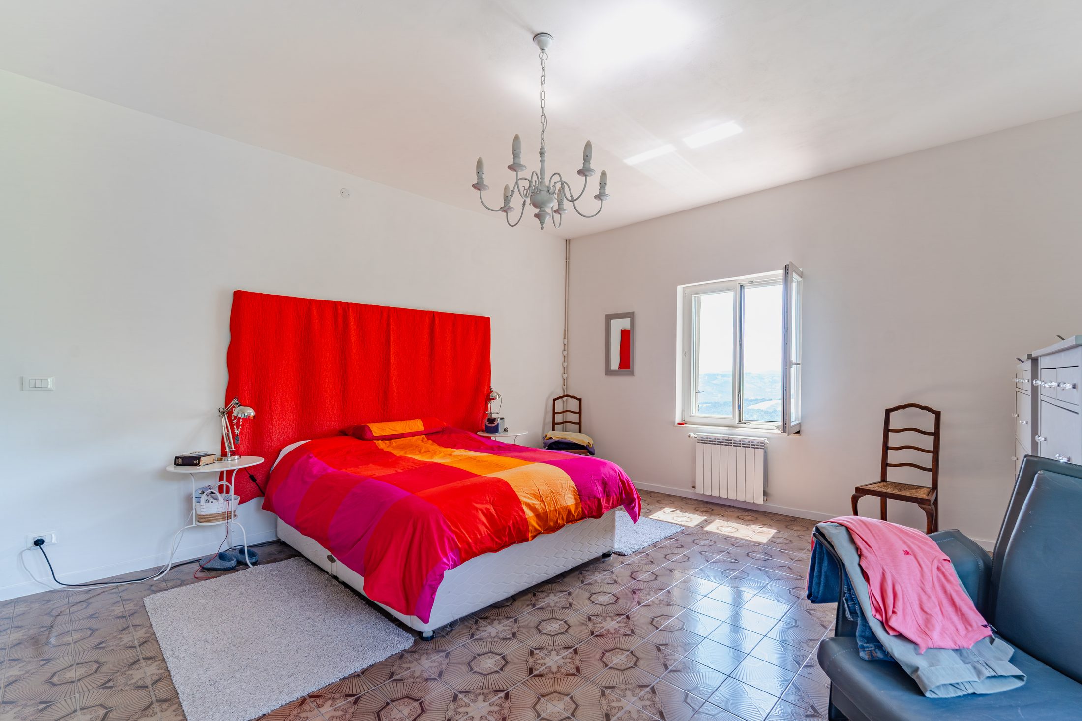 Same bedroom with red headboard and chandelier