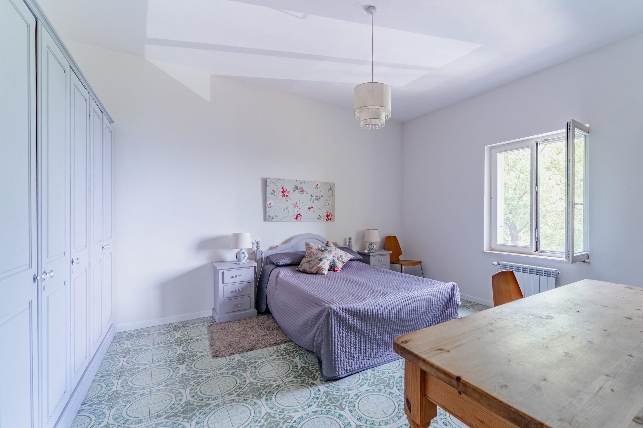 Bedroom with floral artwork and lavender bedspread