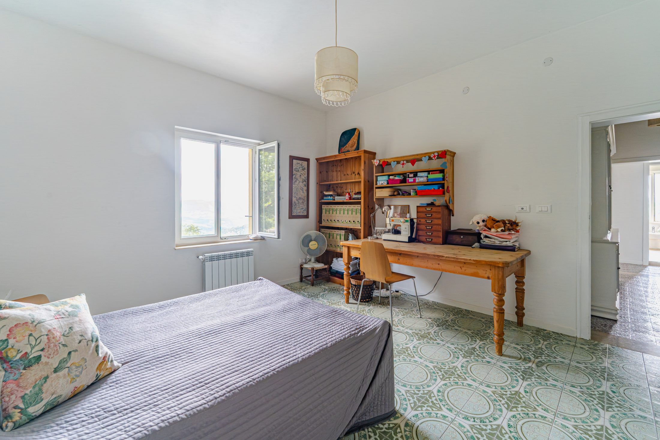 Bedroom with desk, bookshelves and patterned floor tiles