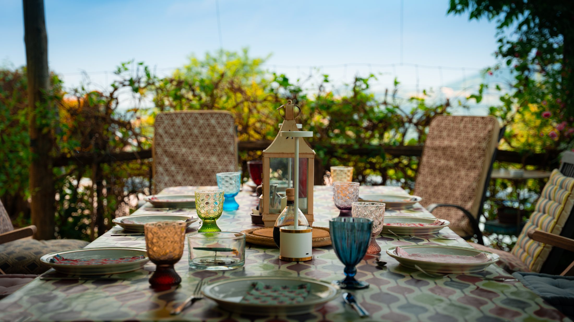 Outdoor table set for a meal under the vine pergola, glassware and valley views